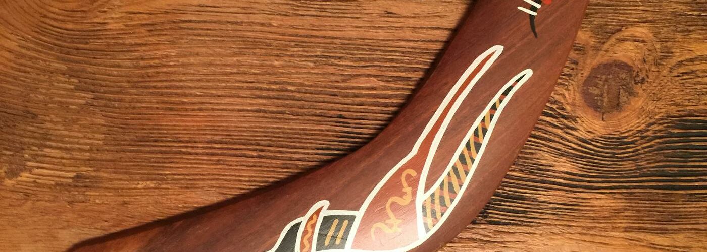 Boomerang aborigène peint posé sur le sable rouge australien