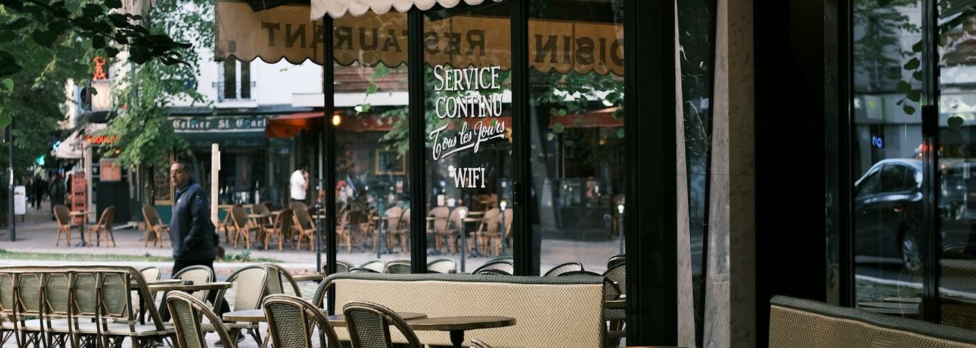 Terrasse de café parisien typique avec chaises en osier et tables rondes