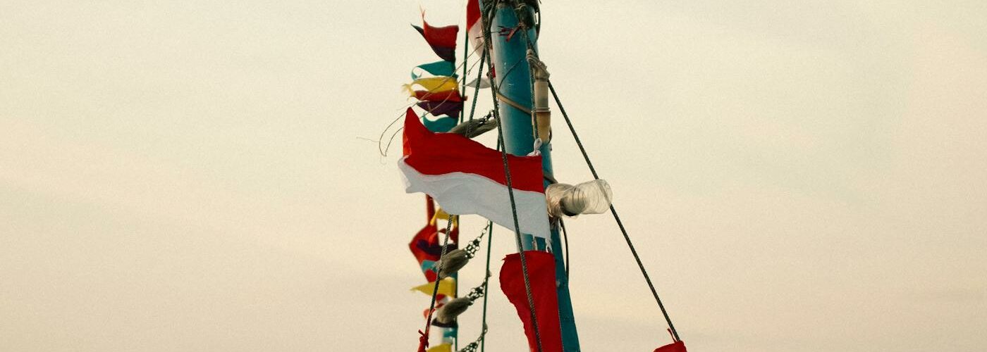 Bateau traditionnel indonésien naviguant en mer avec des drapeaux