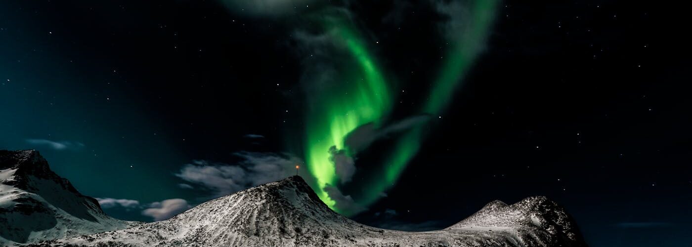 Aurore boréale verte illuminant une montagne enneigée en Norvège